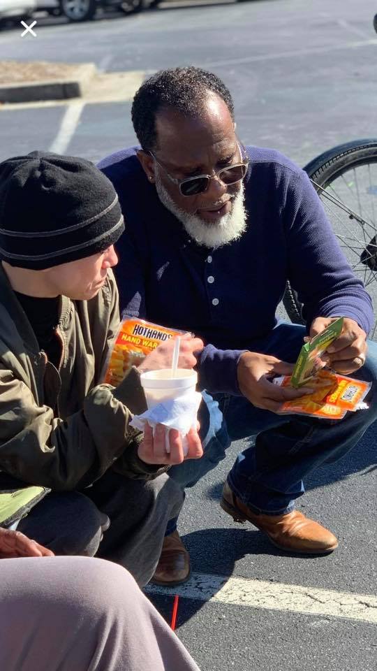 Will Francis from Lives and Souls Missional Church handing food to an individual.